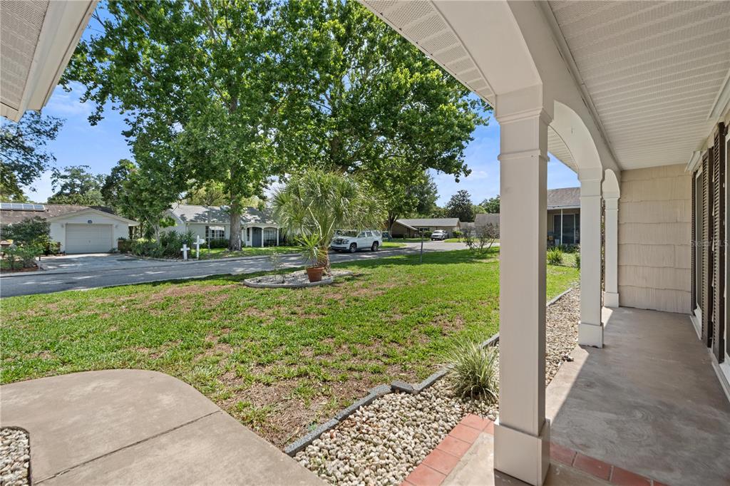 A view from a covered front porch looking out onto a grassy yard and street — 8702 POWDERHORN ROW, HUDSON, FL