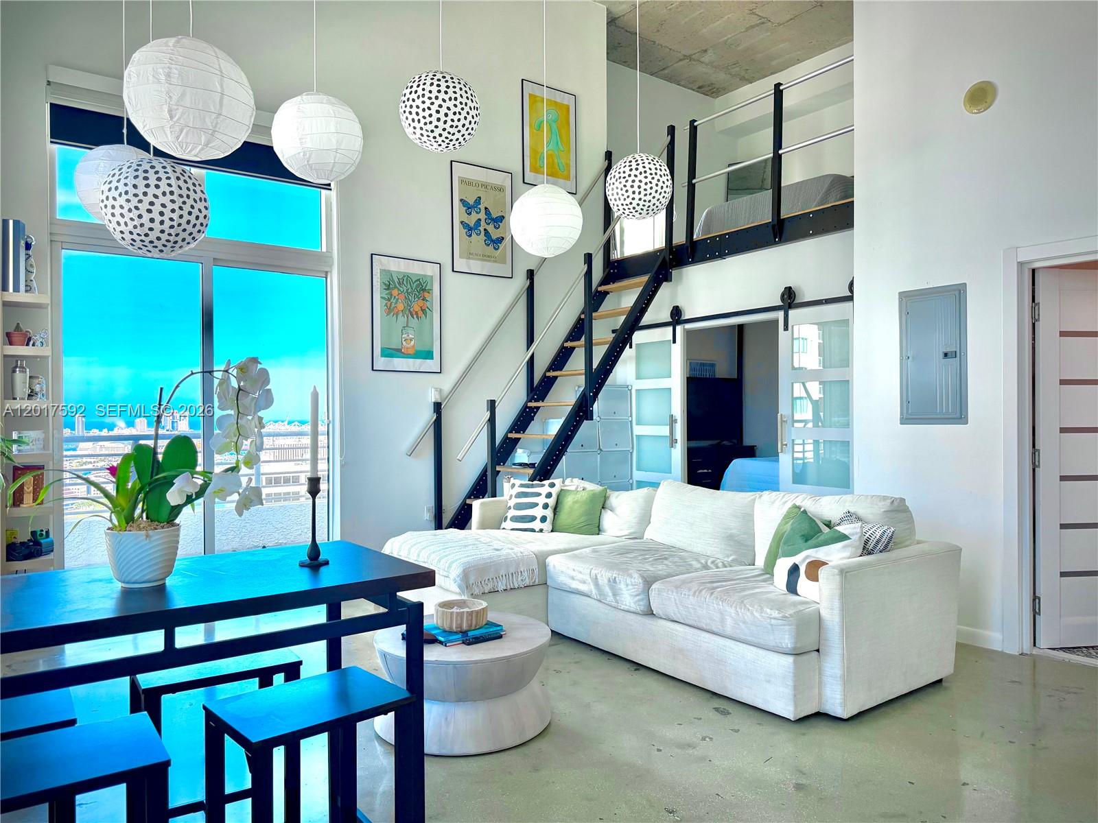 A modern living room with a loft, large windows, and a white sectional sofa — 133 NE 2nd Ave # 3501, Miami FL 33132, MIAMI, FL