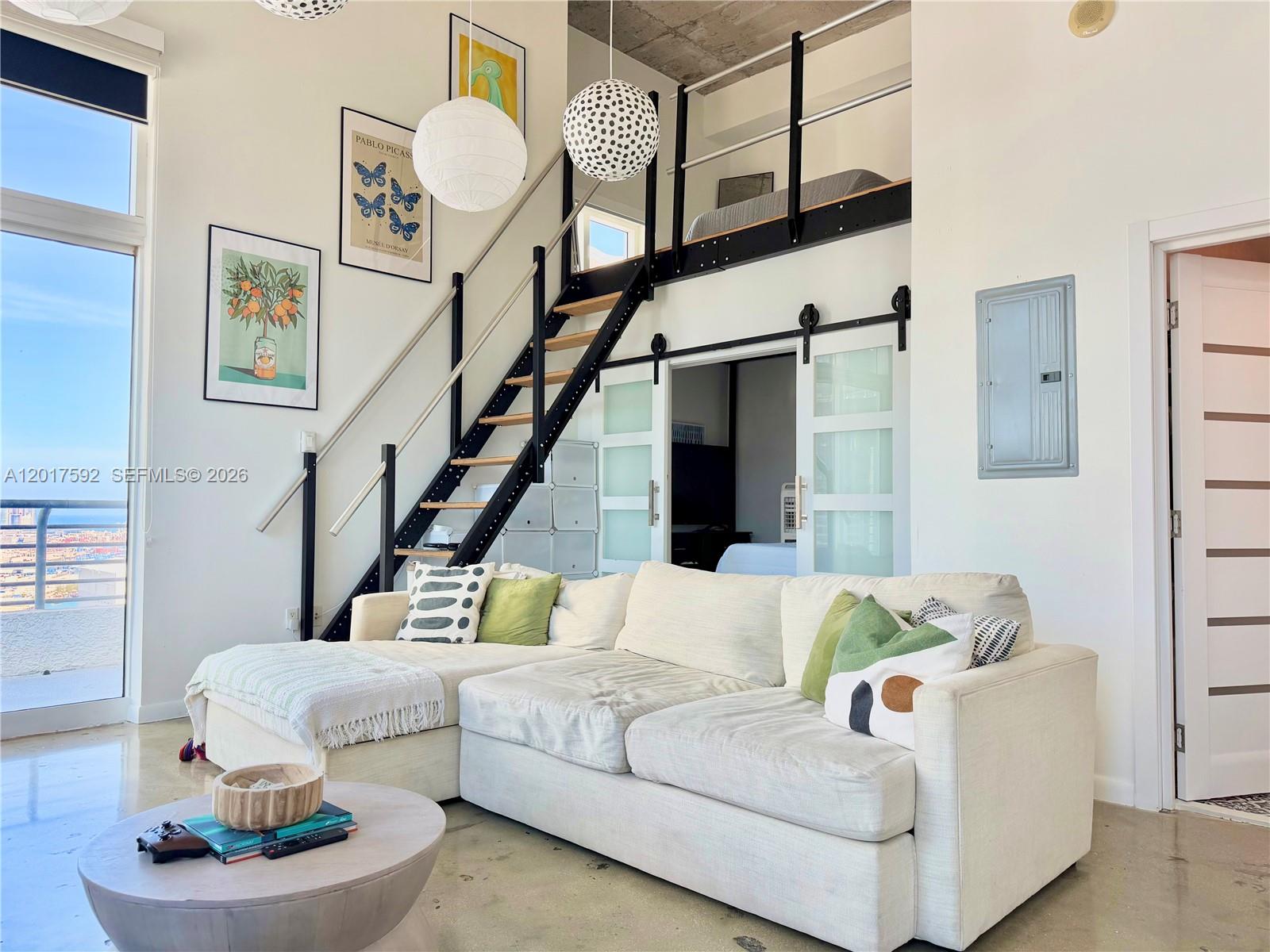 A living room features a white sectional sofa, a lofted sleeping area, and sliding glass doors — 133 NE 2nd Ave # 3501, Miami FL 33132, MIAMI, FL