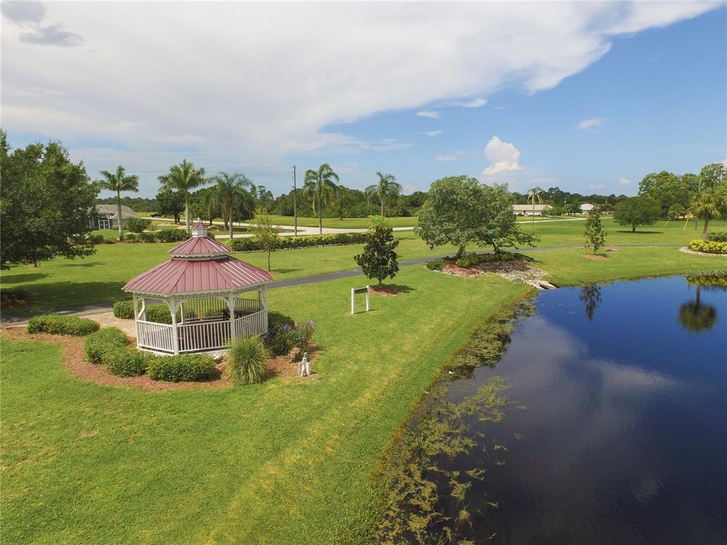 An aerial view shows a white gazebo with a red roof beside a pond — 25219 ALCAZAR DRIVE, PUNTA GORDA, FL