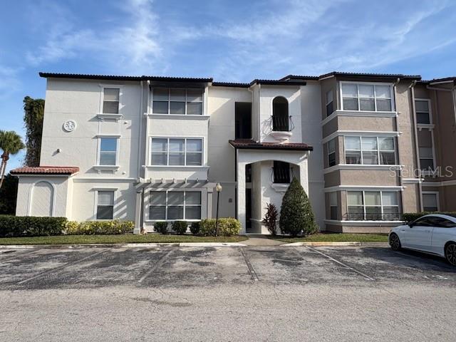 A multi-story apartment building with a beige stucco exterior and a parking lot in front — 5120 CONROY ROAD UNIT 12, ORLANDO, FL