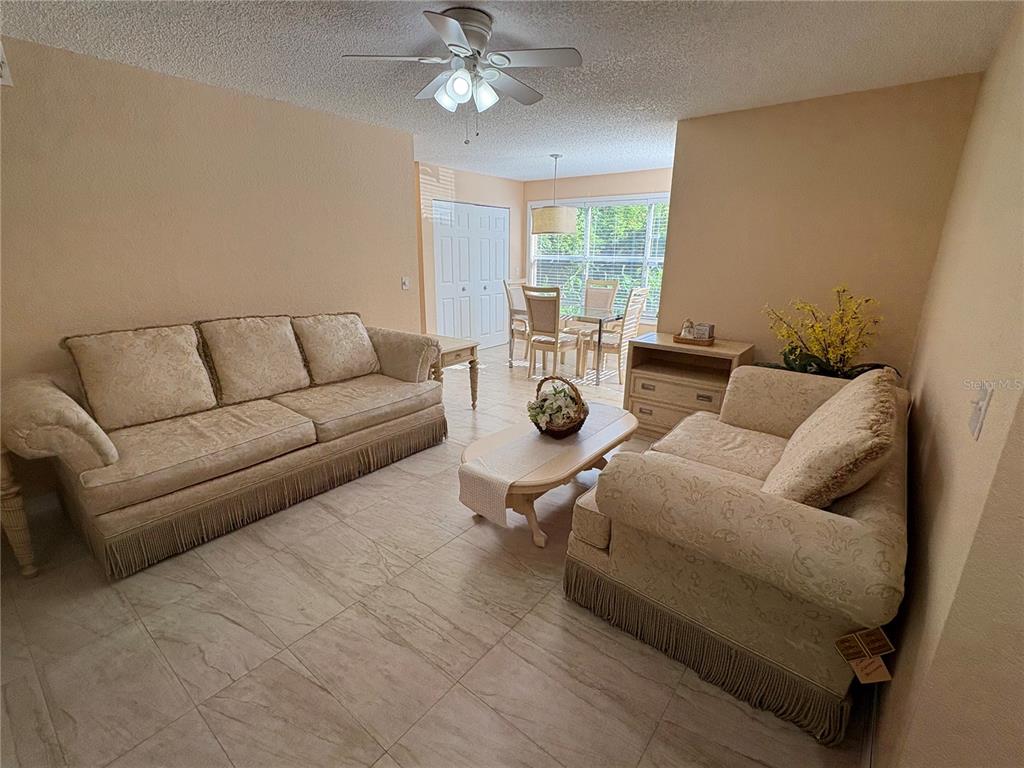 A living room with two beige sofas, a coffee table, and a dining area beyond — 5120 CONROY ROAD UNIT 12, ORLANDO, FL