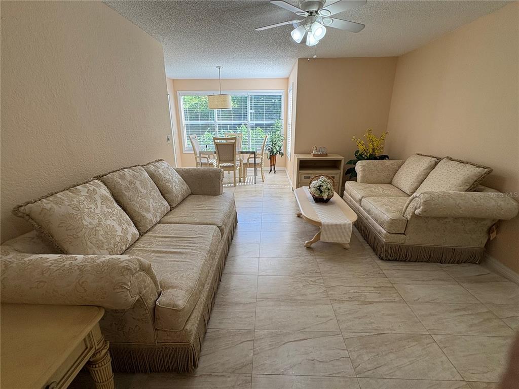 A living room features two beige patterned sofas, a coffee table, and a dining area — 5120 CONROY ROAD UNIT 12, ORLANDO, FL