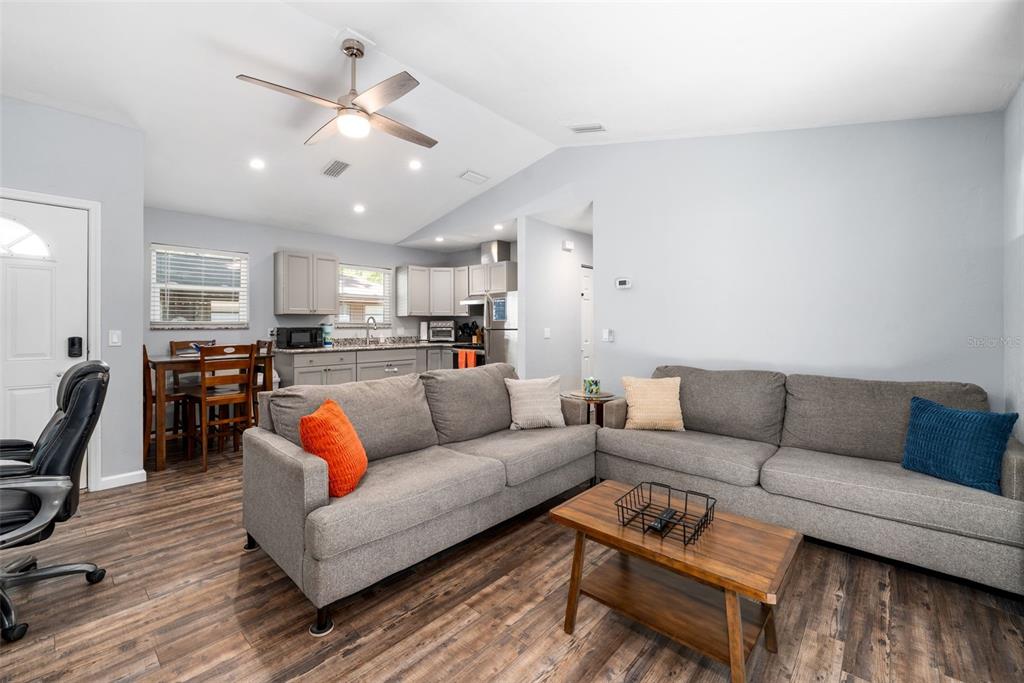 A living room with gray sofas, a wooden coffee table, and an open-concept kitchen — 2256 W UNIVERSITY AVENUE, GAINESVILLE, FL