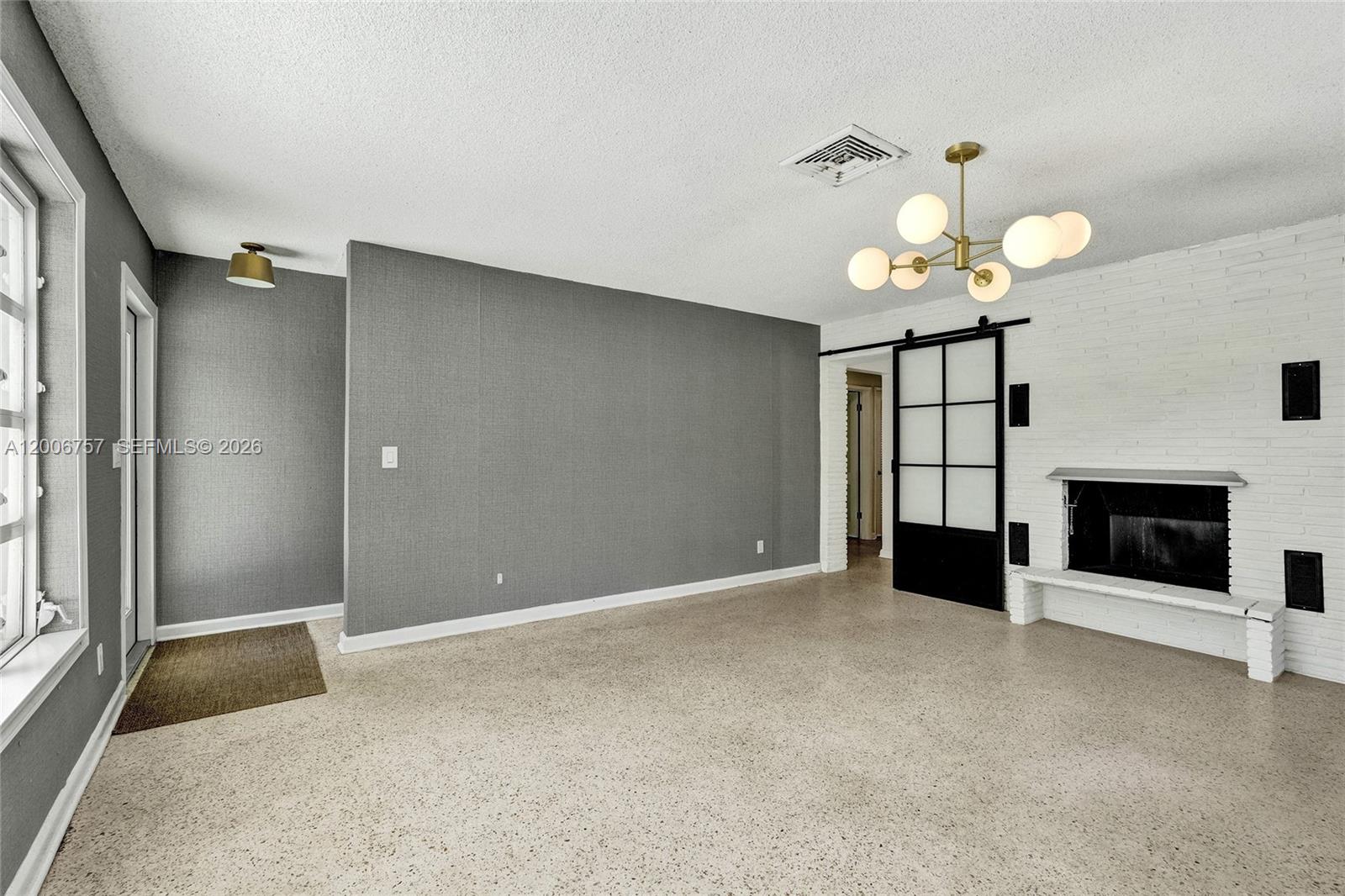 A living room features a white brick fireplace, a modern chandelier, and gray wallpaper — 1421 S Palmway, Lake Worth FL 33460, LAKE WORTH, FL