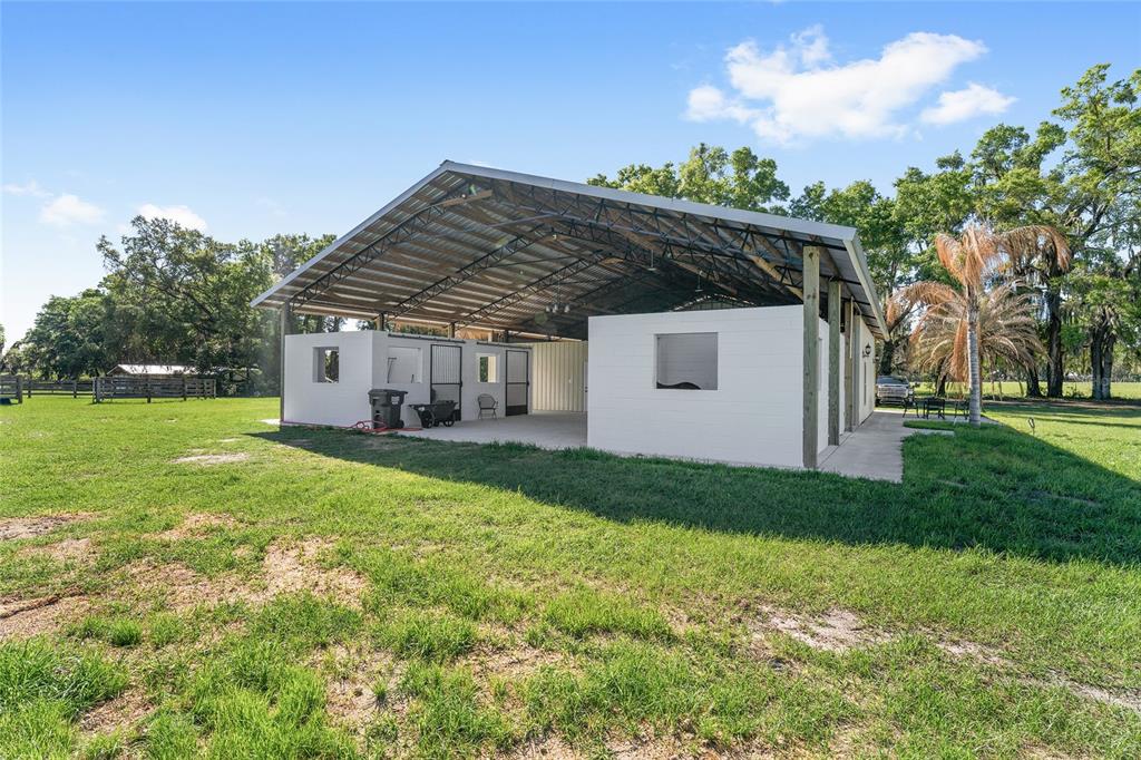 An outdoor horse barn with a metal roof and white concrete block walls — 13869 S HWY 475, SUMMERFIELD, FL