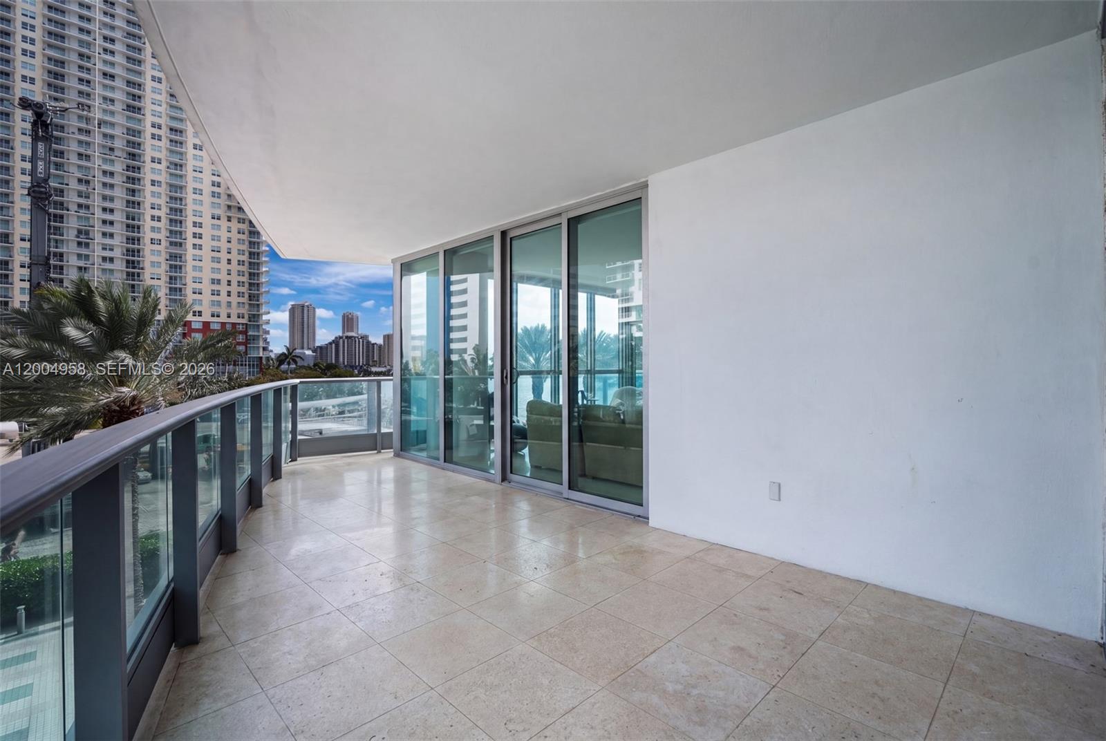 A spacious balcony features light-colored tile flooring, a glass railing, and sliding glass doors — 1331 Brickell Bay Dr # 302, Miami FL 33131, MIAMI, FL