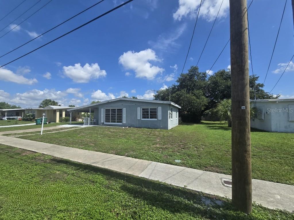 A single-story gray house with a covered porch sits on a grassy corner lot — 21330 HEPNER AVENUE, PORT CHARLOTTE, FL