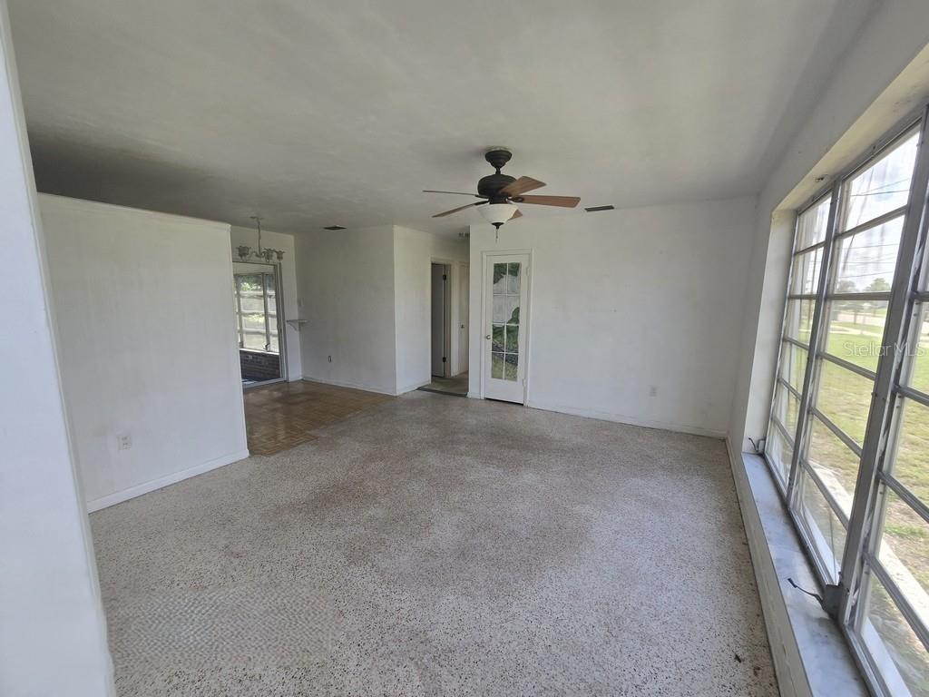 A living room with carpeted floors, a ceiling fan, and large windows overlooking a yard — 21330 HEPNER AVENUE, PORT CHARLOTTE, FL