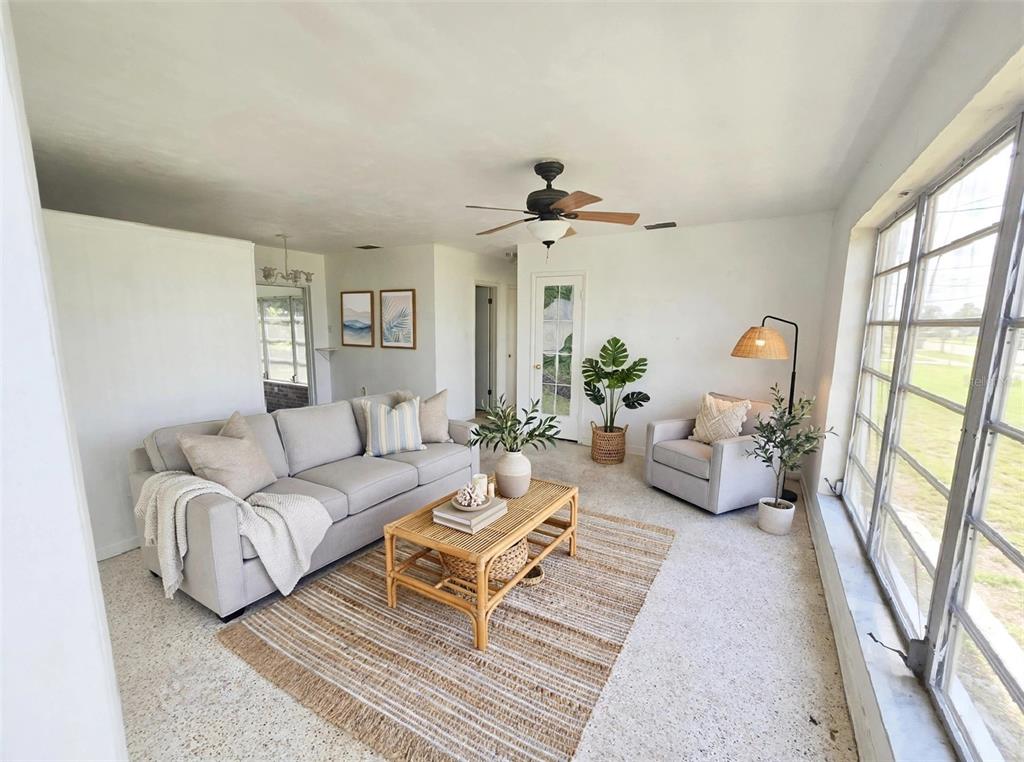 A living room features a light gray sofa, rattan coffee table, and large window wall — 21330 HEPNER AVENUE, PORT CHARLOTTE, FL