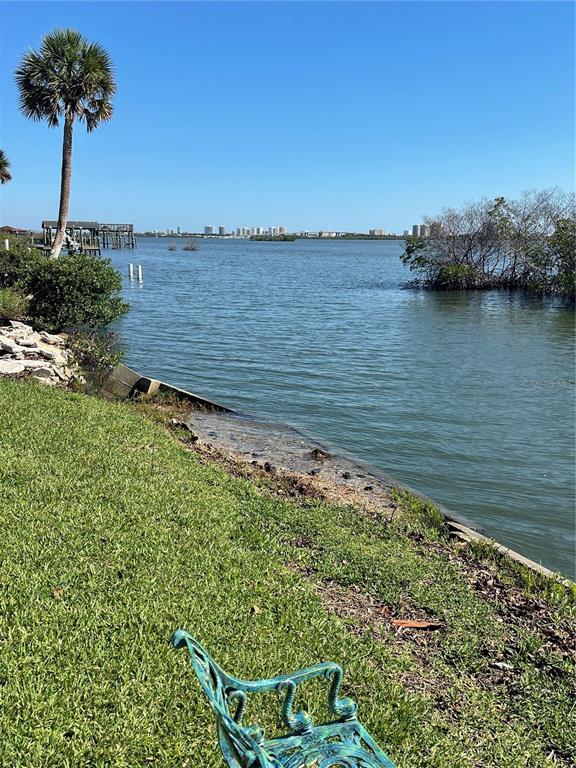 A grassy lawn with a metal bench overlooks a bay with a distant city skyline — 5242 RIVERSIDE DRIVE, PORT ORANGE, FL