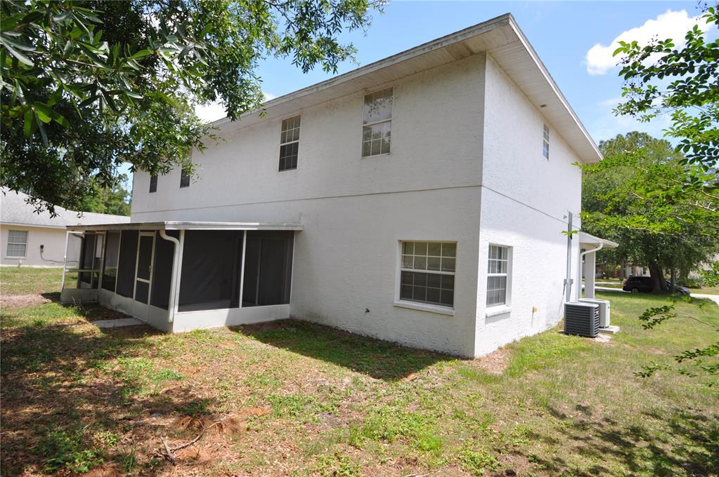 The exterior of a two-story white stucco house features a screened-in porch and yard — 5 WELLS PLACE UNIT A, PALM COAST, FL