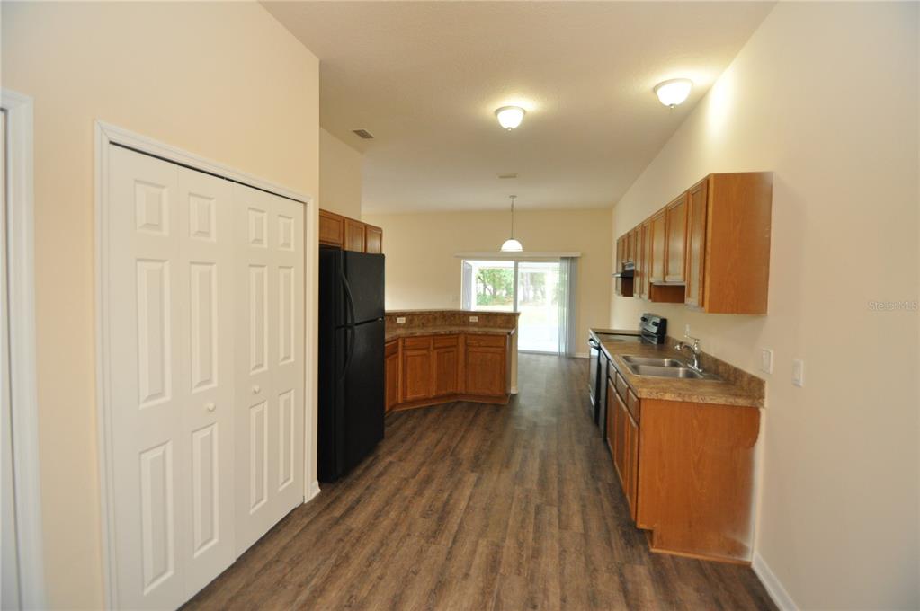 A kitchen features wood cabinets, dark countertops, black appliances, and wood-look flooring — 5 WELLS PLACE UNIT A, PALM COAST, FL