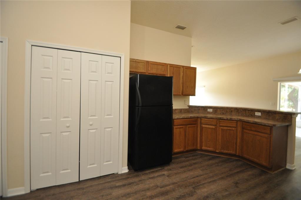 A kitchen features wood cabinets, a black refrigerator, a breakfast bar, and wood-look flooring — 5 WELLS PLACE UNIT A, PALM COAST, FL