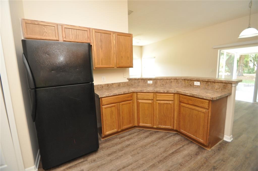 A kitchen features oak cabinets, a black refrigerator, and a brown laminate countertop — 5 WELLS PLACE UNIT A, PALM COAST, FL