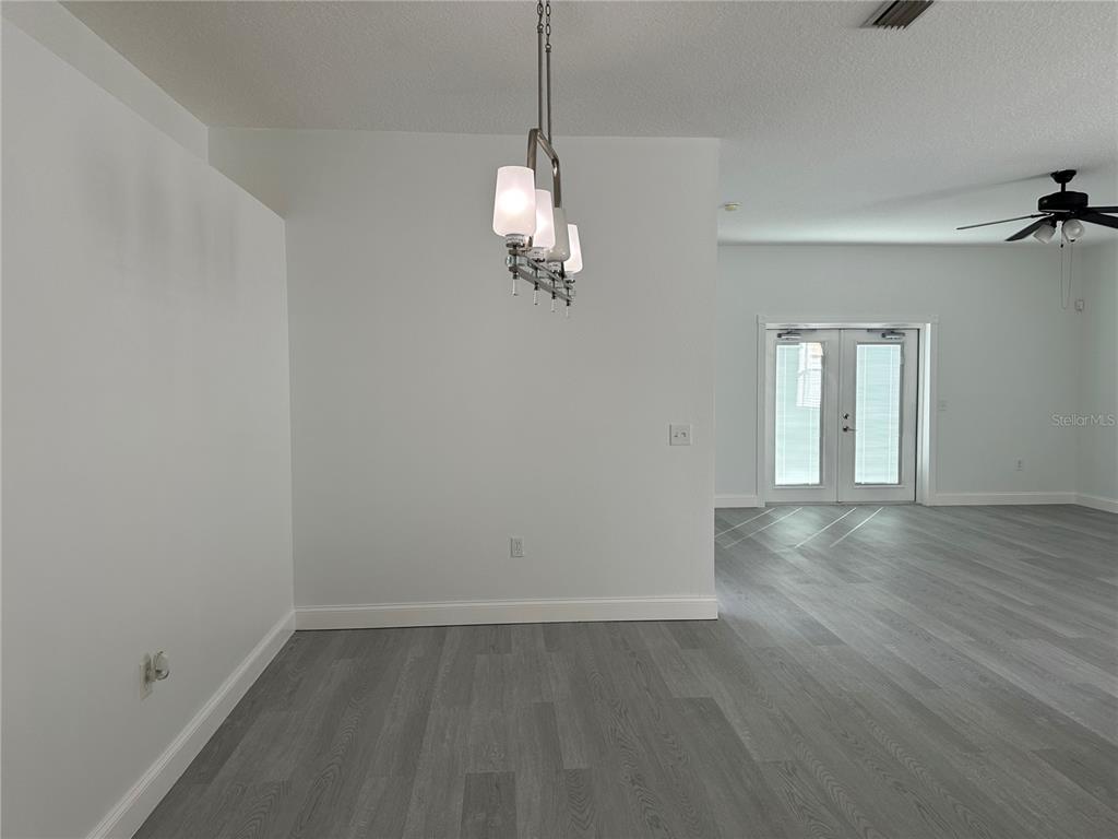 A dining area with a modern light fixture, white walls, and gray wood-look flooring — 24712 PORTOFINO DRIVE, LUTZ, FL