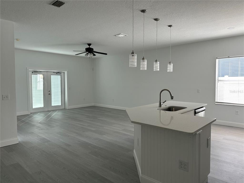 A kitchen island with a sink sits in an open-concept room with light wood flooring — 24712 PORTOFINO DRIVE, LUTZ, FL