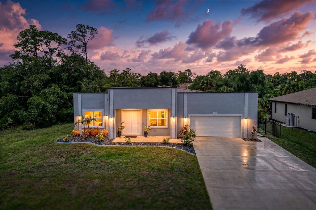 A single-story house with a flat roof, gray stucco exterior, and a two-car garage — 2967 JOHANNESBERG ROAD, NORTH PORT, FL