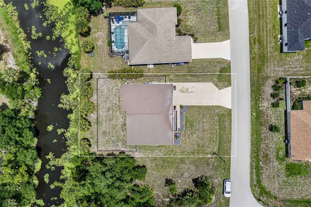 An aerial view shows a single-family home with a fenced backyard bordering a canal — 2967 JOHANNESBERG ROAD, NORTH PORT, FL