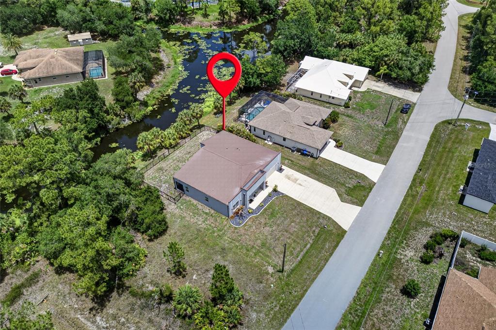 An aerial view shows a suburban house with a brown roof and pool near a pond — 2967 JOHANNESBERG ROAD, NORTH PORT, FL