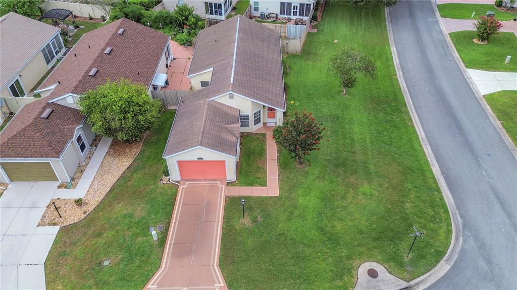 An aerial view shows a single-story house with a tan exterior, brown roof, and garage — 25345 GREEN HERON DRIVE, LEESBURG, FL