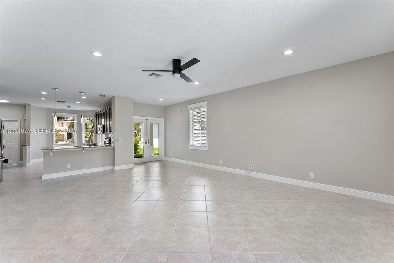 An open-concept living area features light tile flooring, a ceiling fan, and a kitchen island — 1868 Silverbell Ter, Weston FL 33327, WESTON, FL