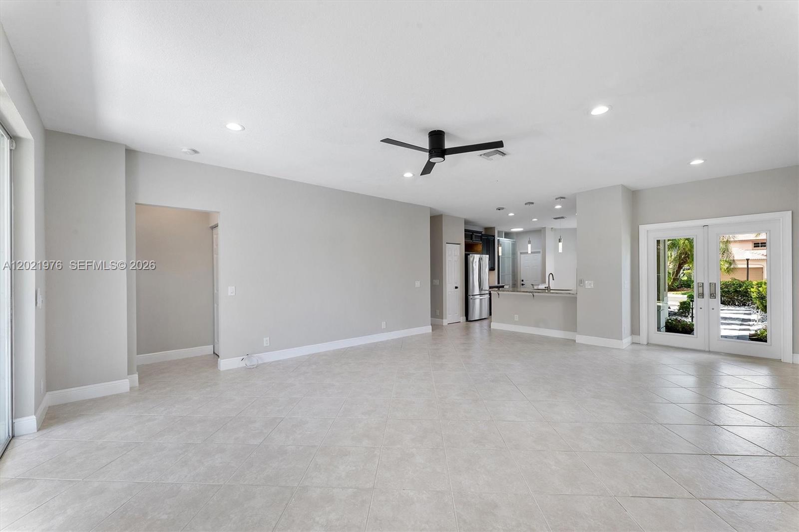 An open-concept living area features light tile flooring, a ceiling fan, and a kitchen — 1868 Silverbell Ter, Weston FL 33327, WESTON, FL