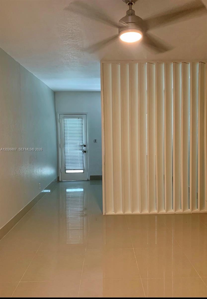 A room with light-colored tile flooring, a ceiling fan, and a vertical slat room divider — 6498 Collins Ave # 41, Miami Beach FL 33141, MIAMI BEACH, FL