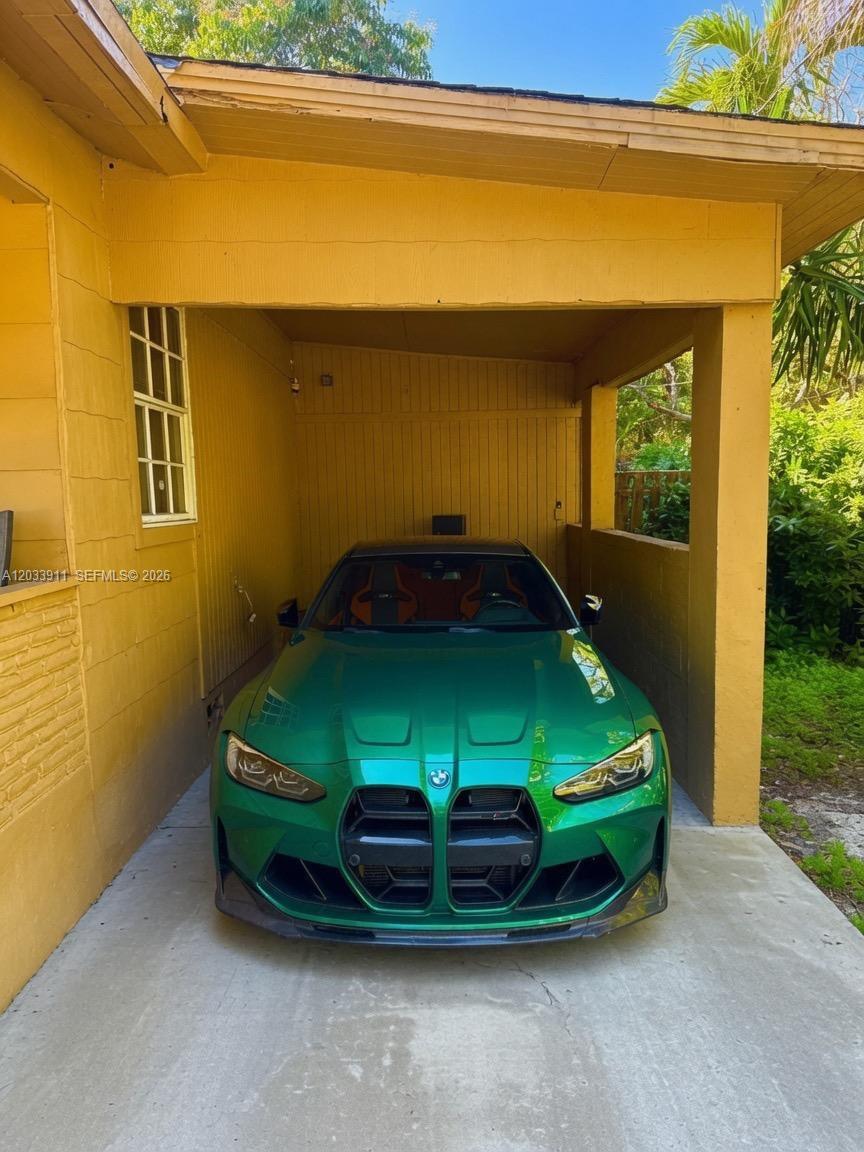 A bright green BMW is parked under a yellow covered carport attached to a house — 1100 N 24th Ave, Hollywood FL 33020, HOLLYWOOD, FL