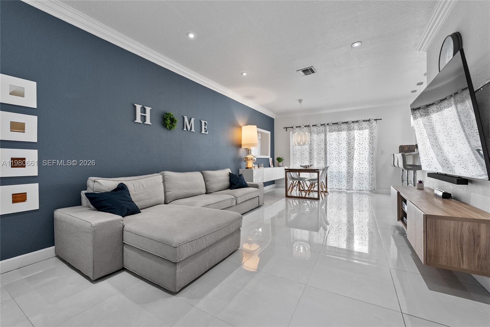 A living room features a blue accent wall, a gray sectional sofa, and white tile flooring — 21474 SW 85th Path, Cutler Bay FL 33189, CUTLER BAY, FL