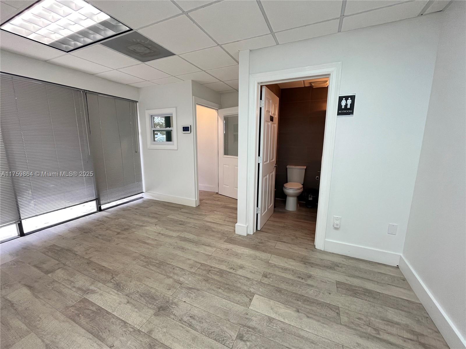 An office space features wood-look flooring, a drop ceiling, and a private restroom — 4350 NW 19th Ave # C, Deerfield Beach FL 33064, DEERFIELD BEACH, FL