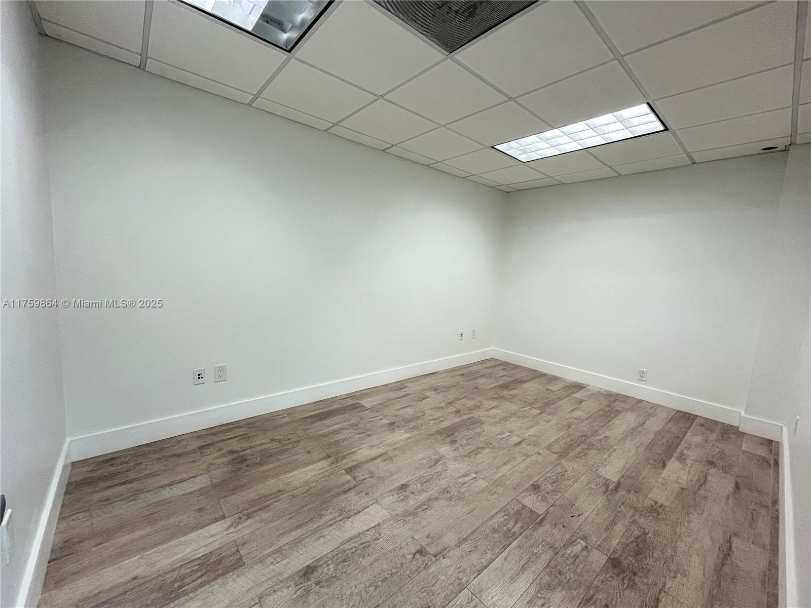 An empty office space features white walls, a drop ceiling, and wood-look laminate flooring — 4350 NW 19th Ave # C, Deerfield Beach FL 33064, DEERFIELD BEACH, FL