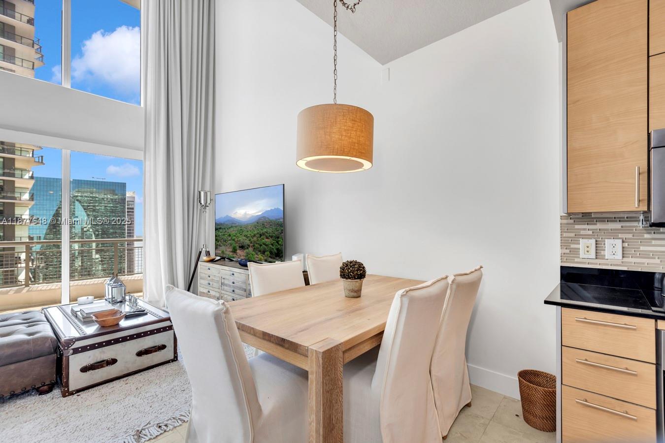 A dining area with a wooden table, four chairs, and a pendant light near windows — 60 SW 13th St # 3402, Miami FL 33130, MIAMI, FL