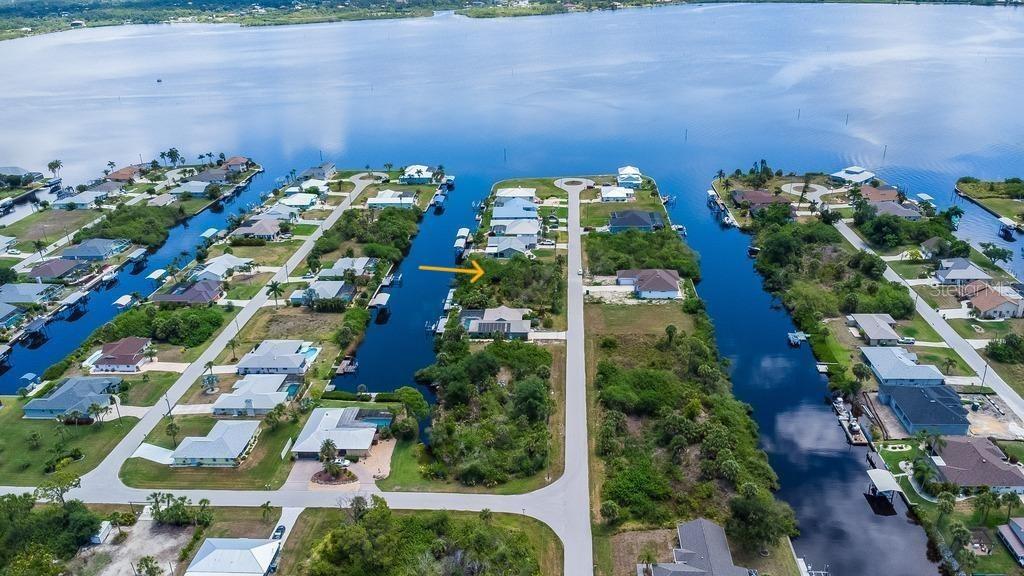 An aerial view of a waterfront residential neighborhood with a vacant lot marked by an arrow — 2425 VANCE TERRACE, PORT CHARLOTTE, FL