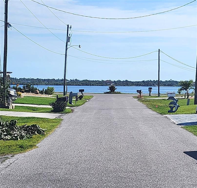 A paved residential street leads toward a waterfront view with utility poles and mailboxes — 2425 VANCE TERRACE, PORT CHARLOTTE, FL