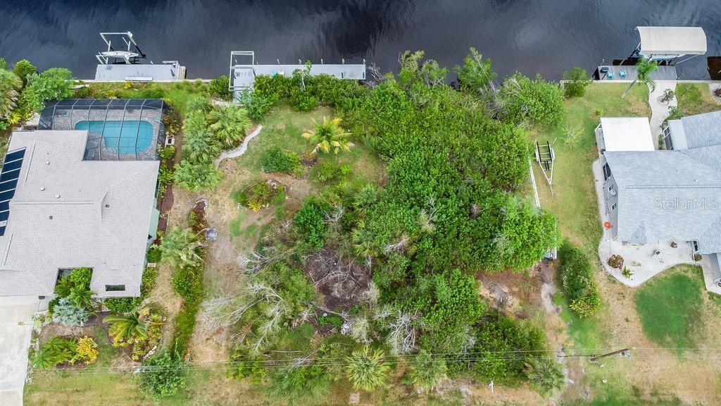 An aerial view shows a vacant waterfront lot situated between two residential properties — 2425 VANCE TERRACE, PORT CHARLOTTE, FL