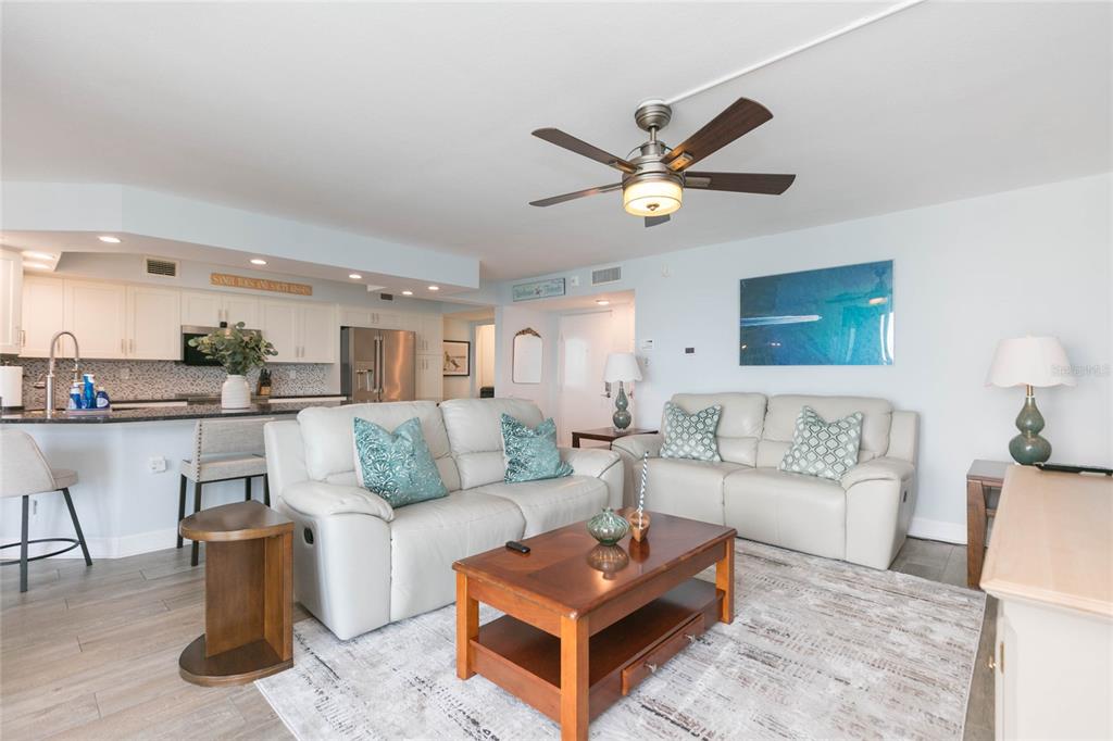 A living room with light-colored leather sofas, a wooden coffee table, and an open kitchen — 5729 PUERTA DEL SOL BOULEVARD S UNIT 381, ST PETERSBURG, FL
