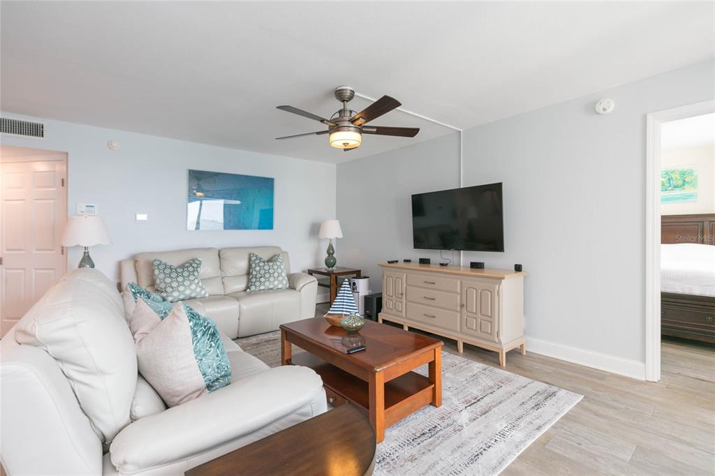 A living room features a white sofa, a wooden coffee table, and a television console — 5729 PUERTA DEL SOL BOULEVARD S UNIT 381, ST PETERSBURG, FL