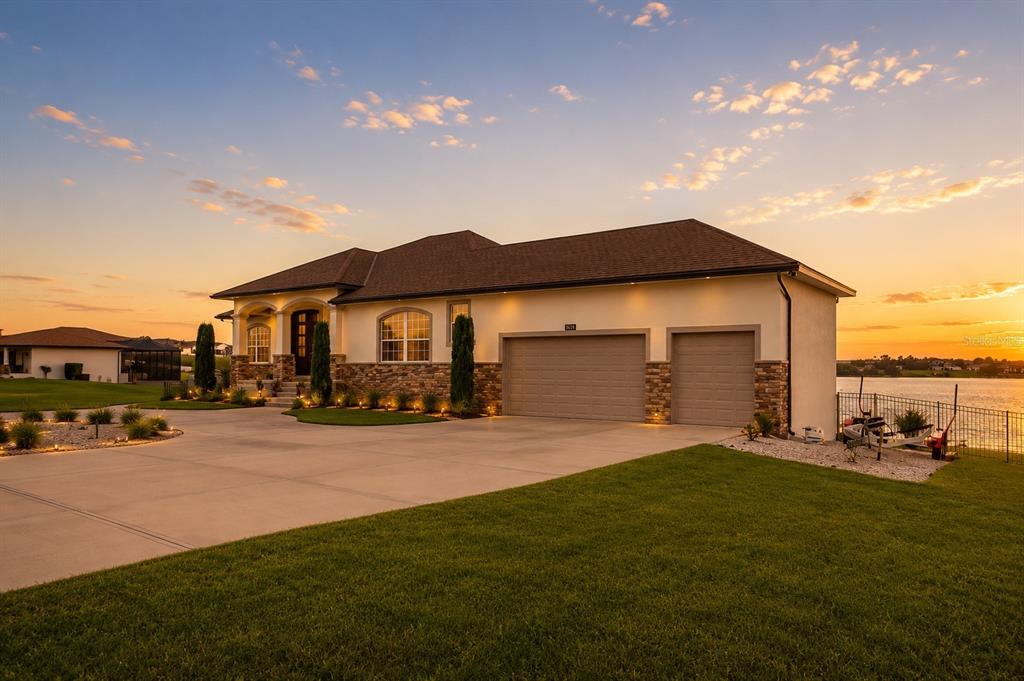 A single-story house with a stone facade, three-car garage, and a large concrete driveway — 5911 OLD BERKLEY ROAD, AUBURNDALE, FL