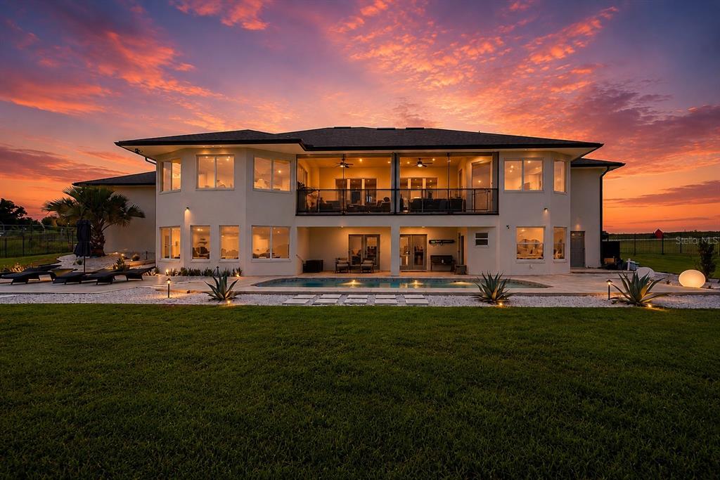 A two-story house with a pool, patio, and balcony under a vibrant sunset sky — 5911 OLD BERKLEY ROAD, AUBURNDALE, FL