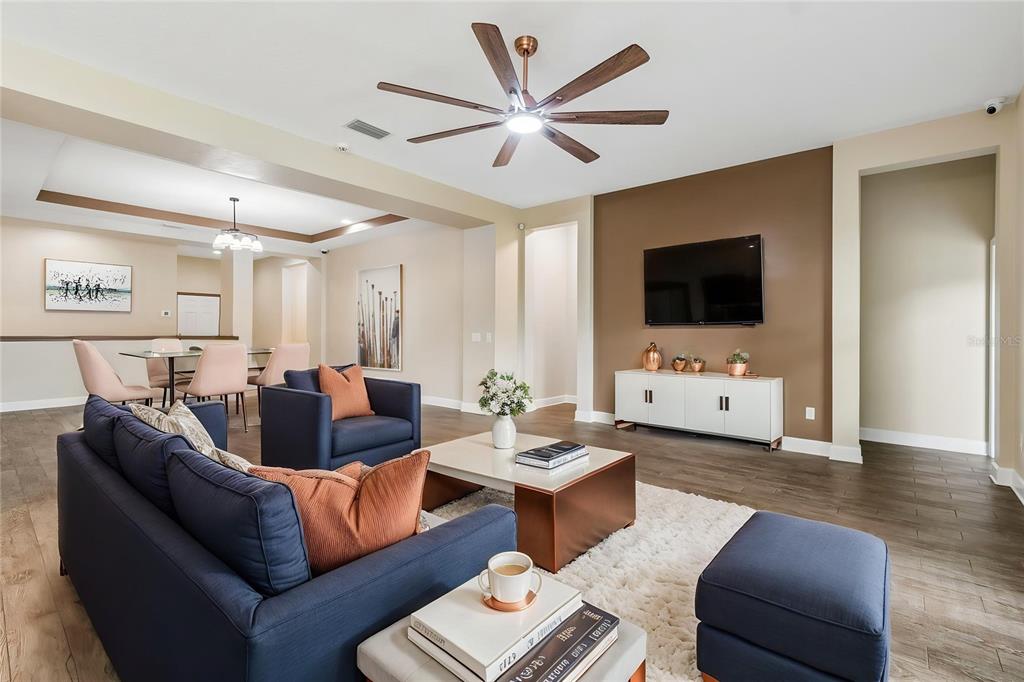 A living room features a blue sofa, a coffee table, and a wall-mounted television — 4930 BUTLER NATIONAL DRIVE, WESLEY CHAPEL, FL