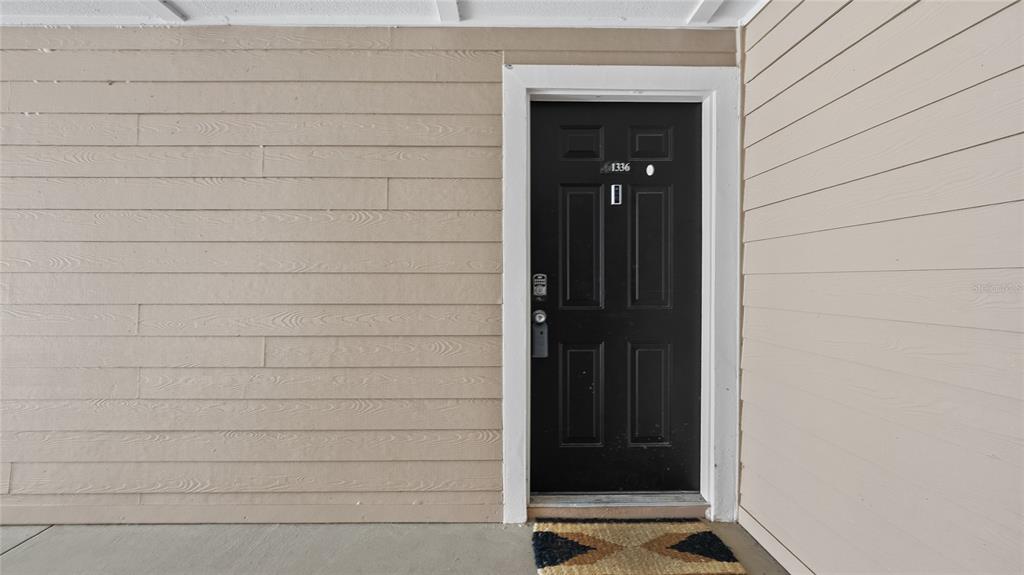 A black front door with the number 1336 is set into tan horizontal siding — 13810 SUTTON PARK DRIVE N UNIT 1336, JACKSONVILLE, FL