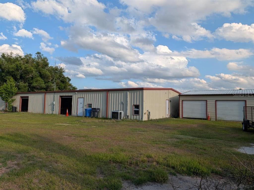 A metal-sided commercial building with multiple garage bays sits on a grassy lot — 4402 GALLAGHER ROAD, PLANT CITY, FL