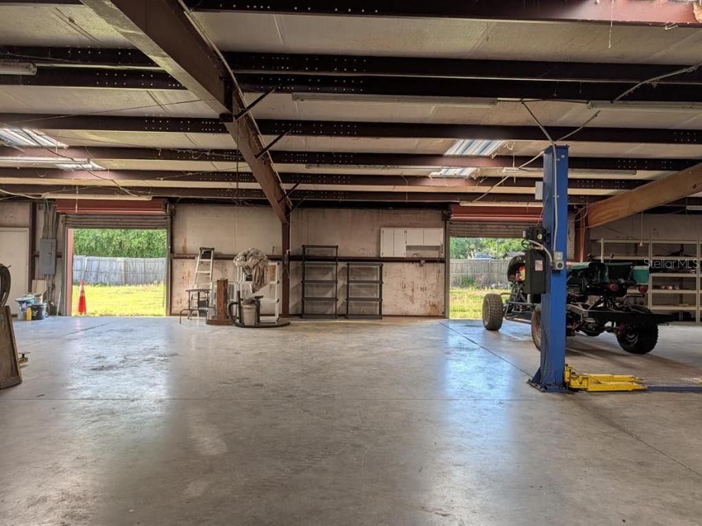 An industrial warehouse space with a concrete floor, exposed steel beams, and a vehicle lift — 4402 GALLAGHER ROAD, PLANT CITY, FL