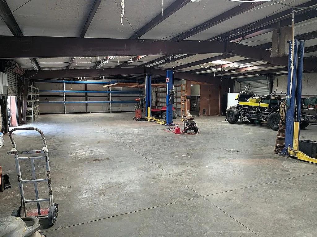 A spacious industrial warehouse interior features concrete floors, exposed steel beams, and vehicle lifts — 4402 GALLAGHER ROAD, PLANT CITY, FL