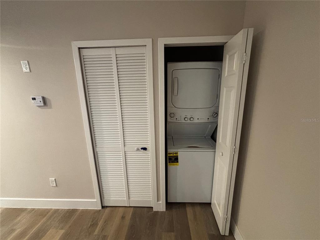 A laundry closet with a stacked washer and dryer sits beside a louvered closet door — 4424 S TEXAS AVENUE UNIT 314, ORLANDO, FL