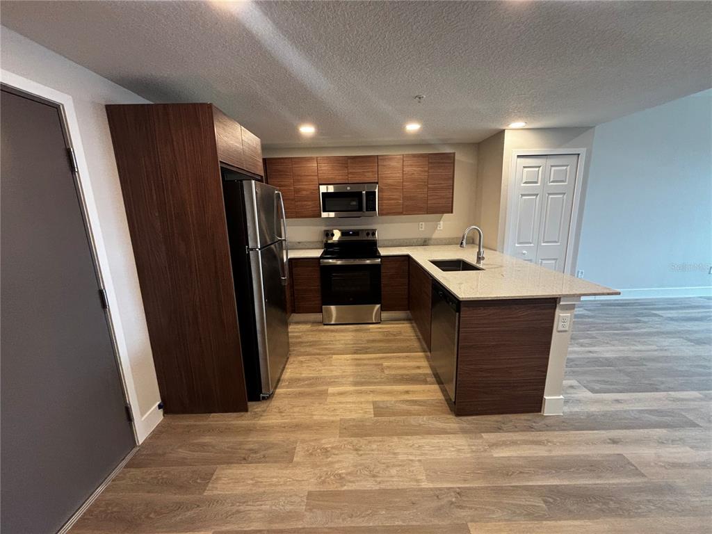 A kitchen features dark wood cabinets, stainless steel appliances, and light-colored countertops — 4424 S TEXAS AVENUE UNIT 314, ORLANDO, FL