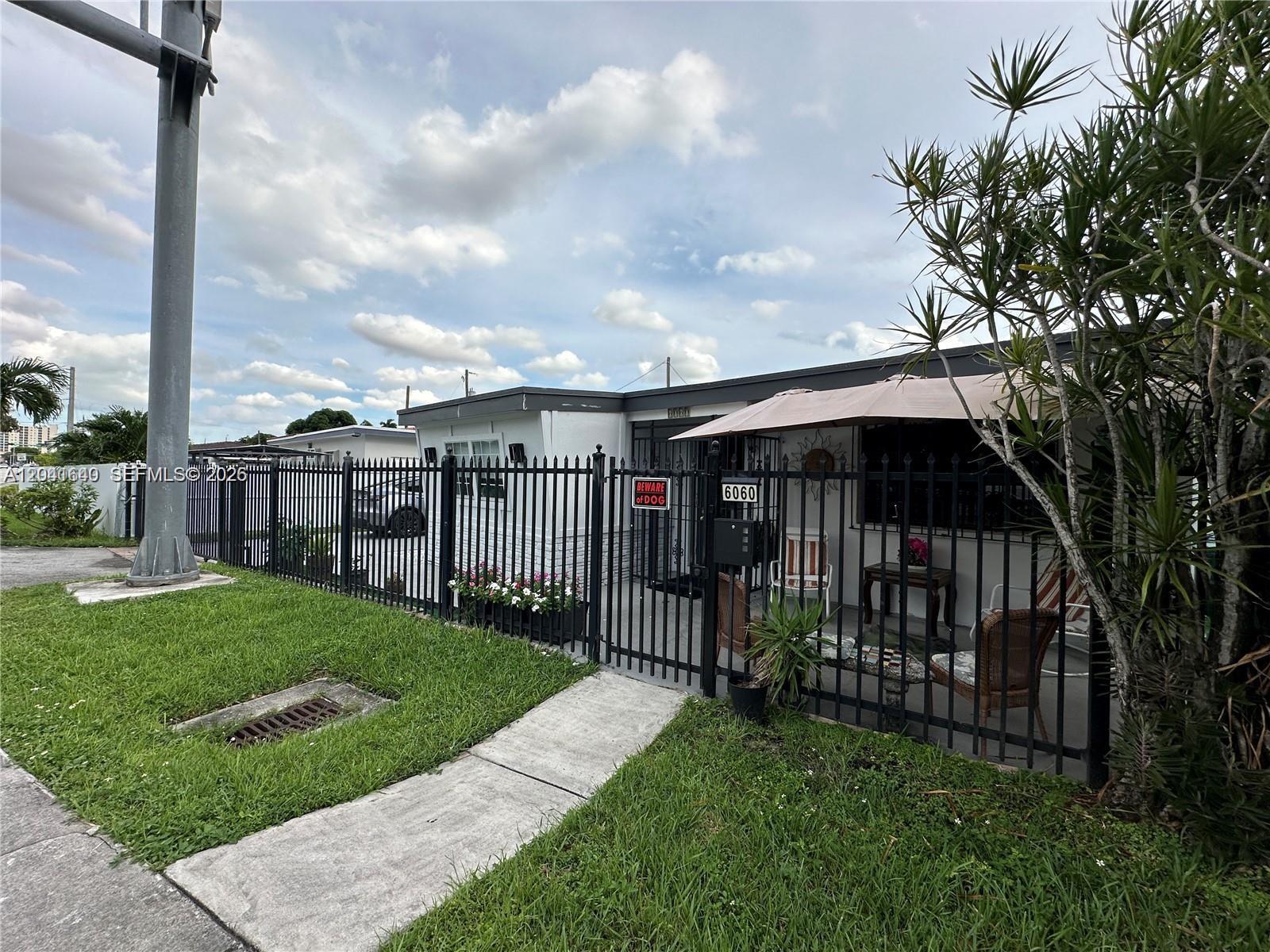 A single-story house with a black metal fence, a patio umbrella, and a front yard — 6060 NW 7th St, Miami FL 33126, MIAMI, FL