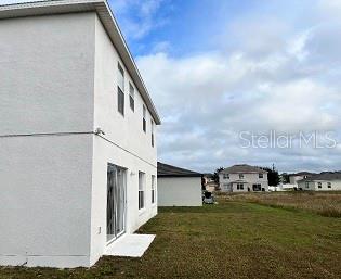 The exterior side view of a two-story white house features a sliding glass door — 1407 NELSON BROOK WAY, KISSIMMEE, FL