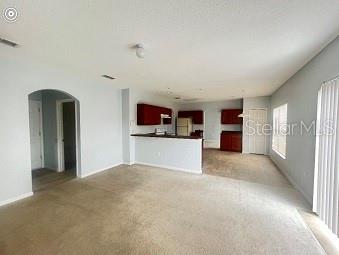 A carpeted living area opens to a kitchen with dark wood cabinets and a breakfast bar — 1407 NELSON BROOK WAY, KISSIMMEE, FL